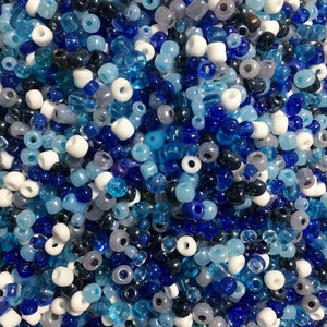 May include: A large assortment of blue, white and grey seed beads. The beads are various shades of blue, including light blue, dark blue and turquoise. There are also some white and grey beads mixed in.