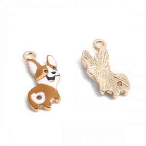 May include: Gold-tone metal charm featuring a cartoon corgi dog with brown, white, and black details. The charm has a loop at the top for attaching to jewelry or other crafts.