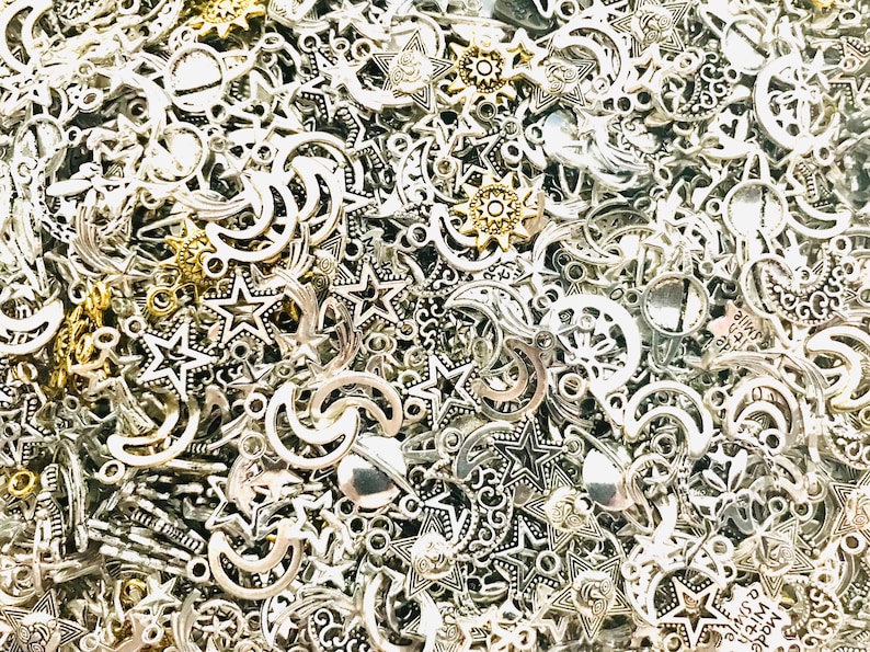 Op de afbeelding: Een grote verzameling zilveren en gouden metalen bedels in de vorm van sterren en halve manen.