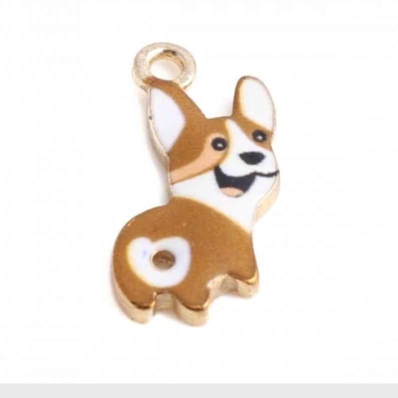 May include: Gold charm featuring a cartoon corgi with brown, white, and black markings. The corgi is smiling and has a heart-shaped patch on its rear end.