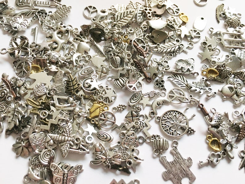 Puede incluir: Un gran surtido de colgantes de amuleto de plata con varios dise&ntilde;os, incluyendo signos de paz, estrellas, hojas, mariposas y mucho m&aacute;s. Los colgantes son perfectos para agregar un toque personal a los proyectos de joyer&iacute;a.