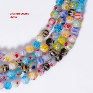May include: Close-up of colourful glass beads with floral patterns. The beads are approximately 4mm in diameter and are arranged in a row.