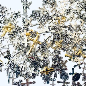 May include: A large collection of silver and gold cross charms. The charms are of various sizes and designs, with some featuring intricate details.