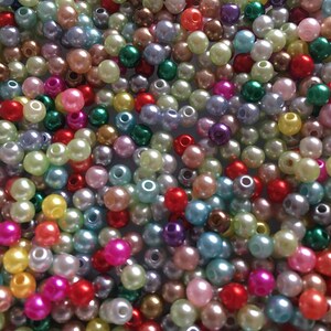 May include: A large assortment of colorful plastic pearl beads. The beads are in various shades of pink, blue, green, yellow, red, and purple.