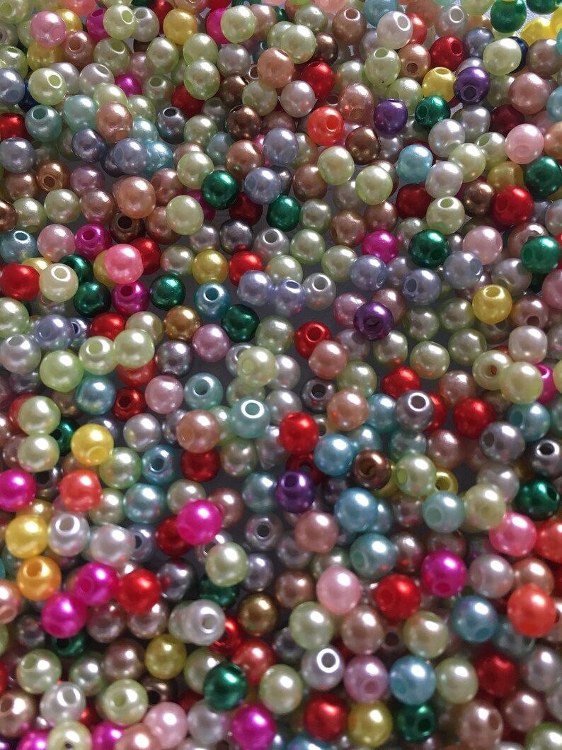 May include: A large assortment of colorful plastic pearl beads. The beads are in various shades of pink, blue, green, yellow, red, and purple.
