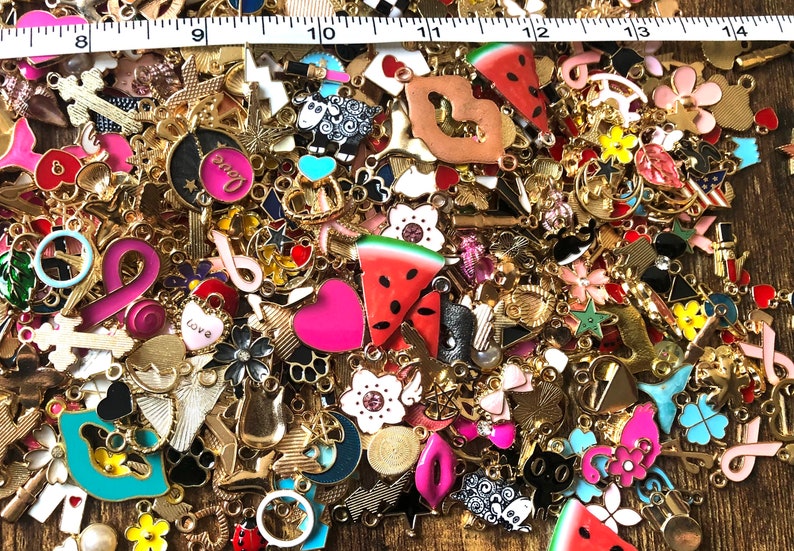 以下が含まれることがあります： ハート、星、花、動物など、カラフルな金属製のチャームがたくさんあります。チャームはすべてゴールドトーンで、さまざまなデザインがあります。チャームの中には、「love」や「peace」などの言葉が書かれたものもあります。