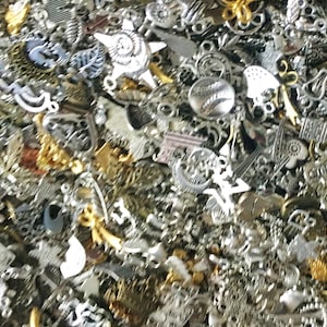 Puede incluir: Un gran surtido de abalorios de metal plateado y dorado. Los abalorios son de diversas formas y tama&ntilde;os, incluyendo corazones, estrellas y flores.