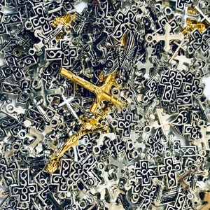 May include: A large pile of silver and gold cross charms. The charms are all different shapes and sizes, and some have intricate designs.