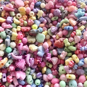 May include: A large assortment of colorful plastic beads in various shapes, including stars, hearts, seashells, and flowers. The beads are perfect for crafting jewelry, making bracelets, or adding a touch of whimsy to any project.