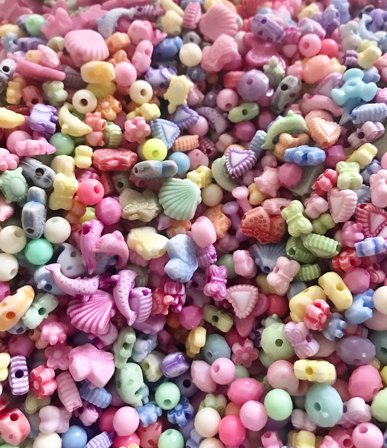 May include: A large assortment of colorful plastic beads in various shapes, including stars, hearts, seashells, and flowers. The beads are perfect for crafting jewelry, making bracelets, or adding a touch of whimsy to any project.