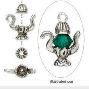 Puede incluir: Encanto de plata en forma de tetera con un cristal verde. El encanto se muestra en tres posiciones diferentes, incluyendo un primer plano del cristal.