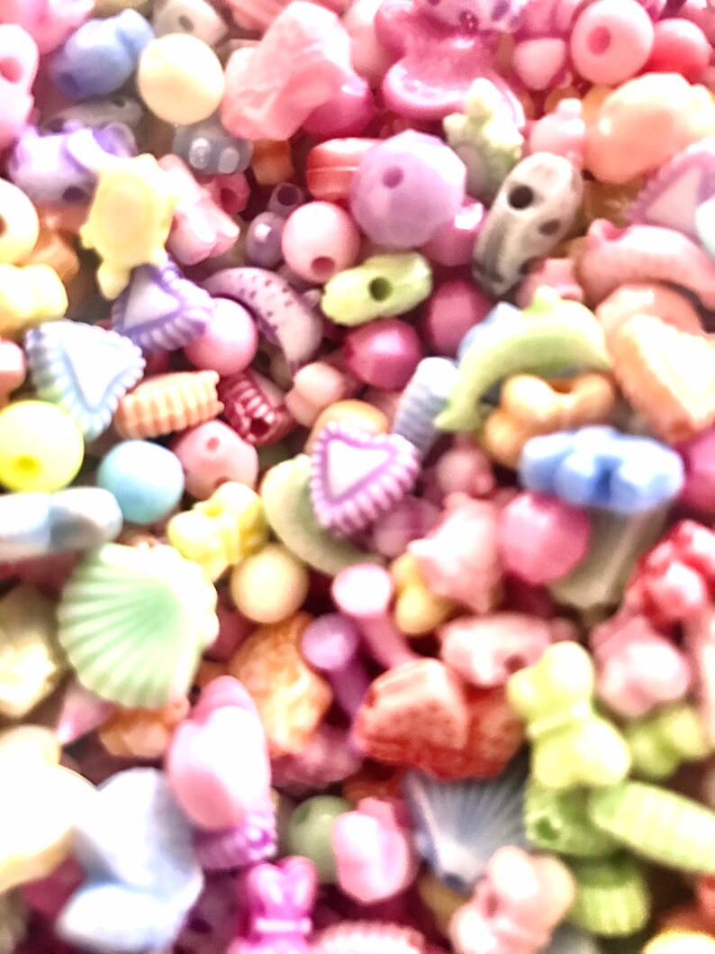 May include: A large assortment of colorful plastic beads in various shapes, including hearts, stars, shells, and flowers. The beads are perfect for crafting jewelry, making hair accessories, or adding a touch of whimsy to any project.