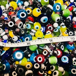 Pu&ograve; includere: Una grande collezione di perline di vetro colorate con un design di occhio turco. Le perline sono di varie forme e dimensioni, tra cui rotonde, ovali e quadrate. Le perline sono un mix di blu, verde, giallo, rosso e bianco.
