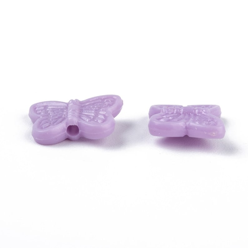 Op de afbeelding: Twee paarse plastic vlinder kralen met een gat in het midden om te rijgen.