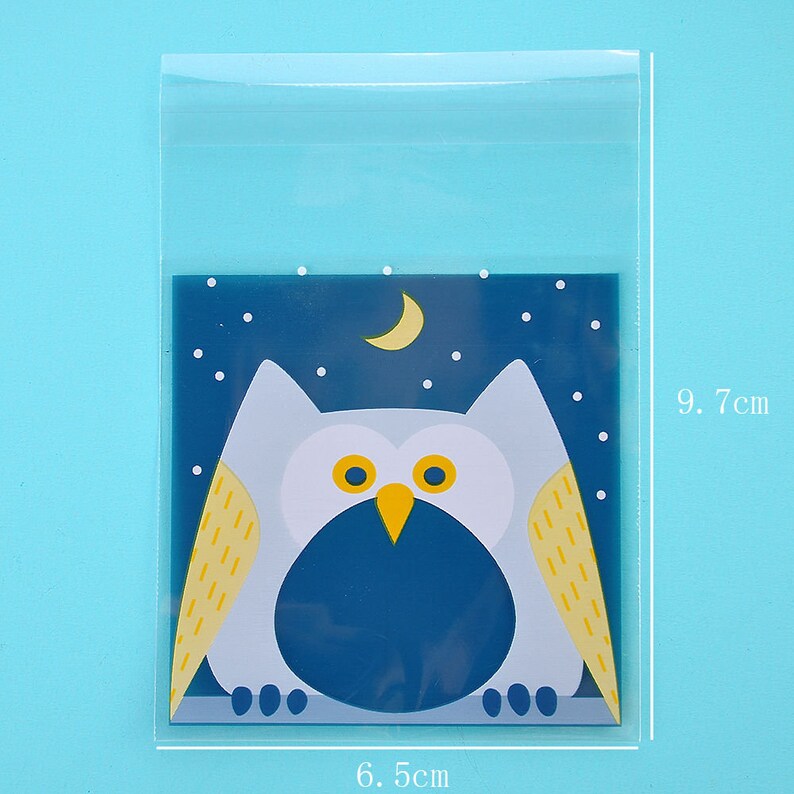 May include: Clear plastic bag with a blue and white owl design. The owl has yellow feathers and a crescent moon is in the background. The bag measures 6.5 cm by 9.7 cm.