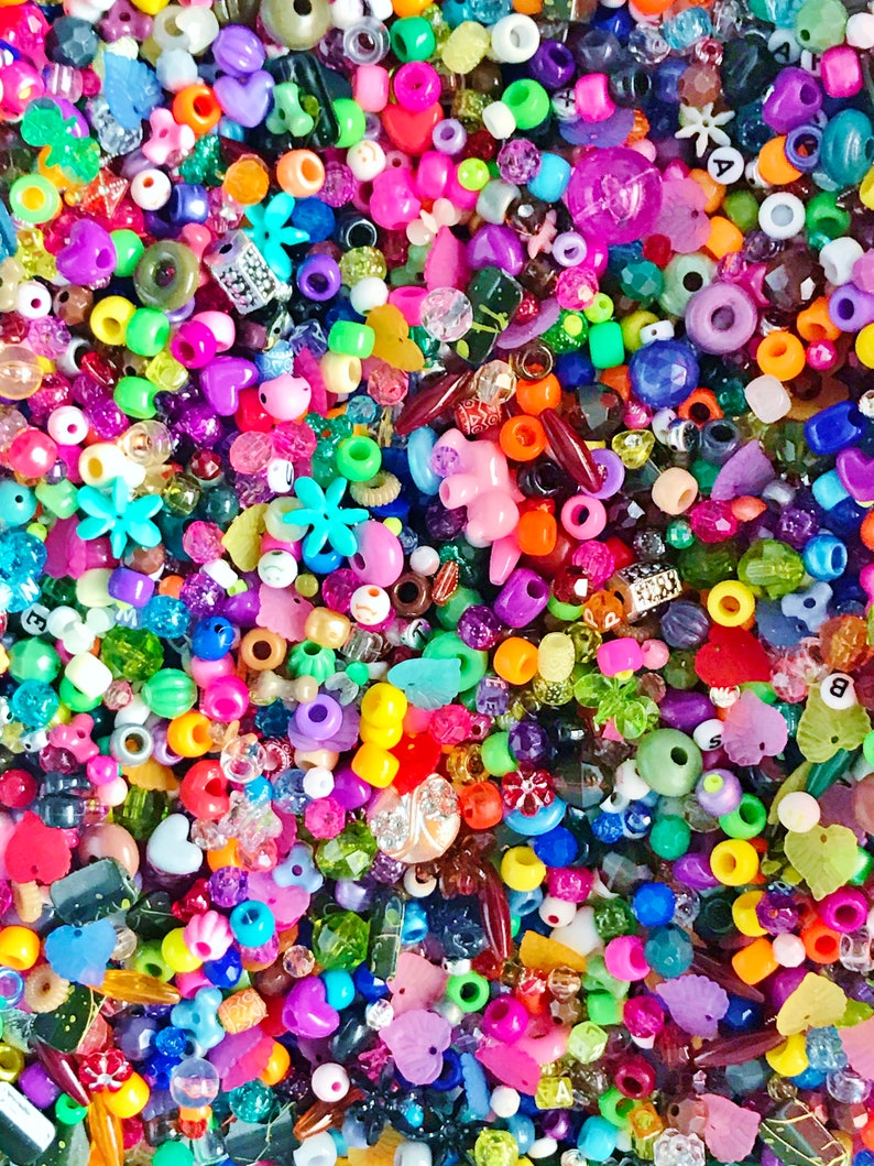 May include: A large assortment of colorful plastic beads in various shapes and sizes, including hearts, stars, flowers, and letters. The beads are perfect for crafting jewelry, making bracelets, necklaces, and other accessories.