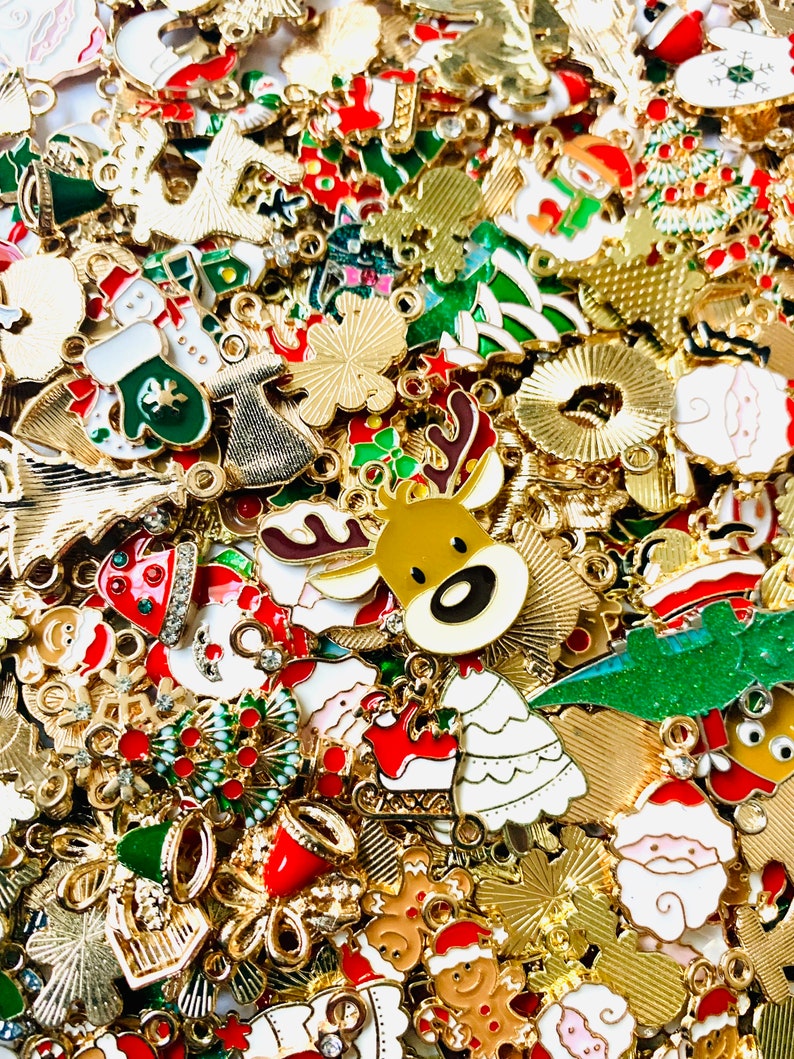 May include: A large assortment of gold-tone metal Christmas charms featuring various holiday themes. The charms include reindeer, Santa Claus, Christmas trees, bells, snowflakes, and other festive designs.