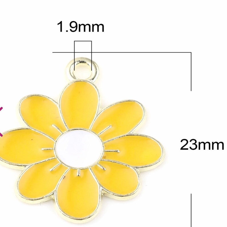 Puede incluir: Un amuleto de metal dorado en forma de flor amarilla con un centro blanco. El amuleto mide 23 mm de ancho y 1,9 mm de grosor.
