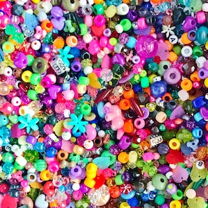 May include: A large assortment of colorful beads in various shapes and sizes, including hearts, stars, flowers, and letters. The beads are made of plastic, glass, and metal.