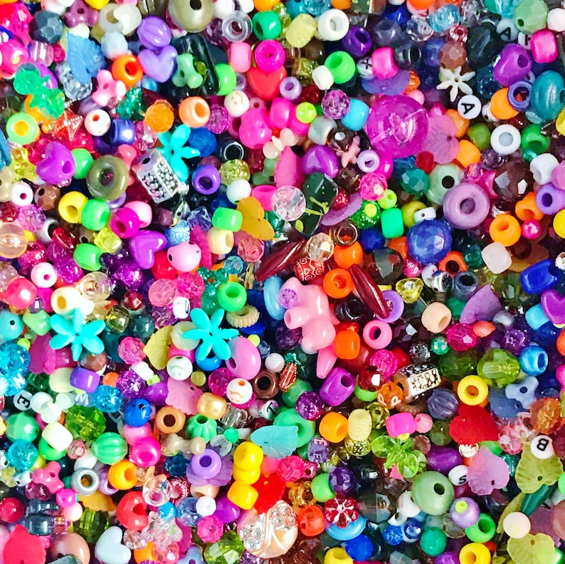 May include: A large assortment of colorful beads in various shapes and sizes, including hearts, stars, flowers, and letters. The beads are made of plastic, glass, and metal.