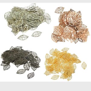 Puede incluir: Surtido de abalorios de hojas de metal en oro, plata, negro y oro rosa. Las hojas son delicadas e intrincadas, con un diseño recortado.