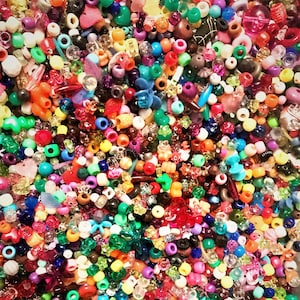 May include: A large assortment of colorful plastic beads in various shapes and sizes. The beads are a mix of opaque and translucent colors, including red, blue, green, yellow, orange, purple, pink, and white.