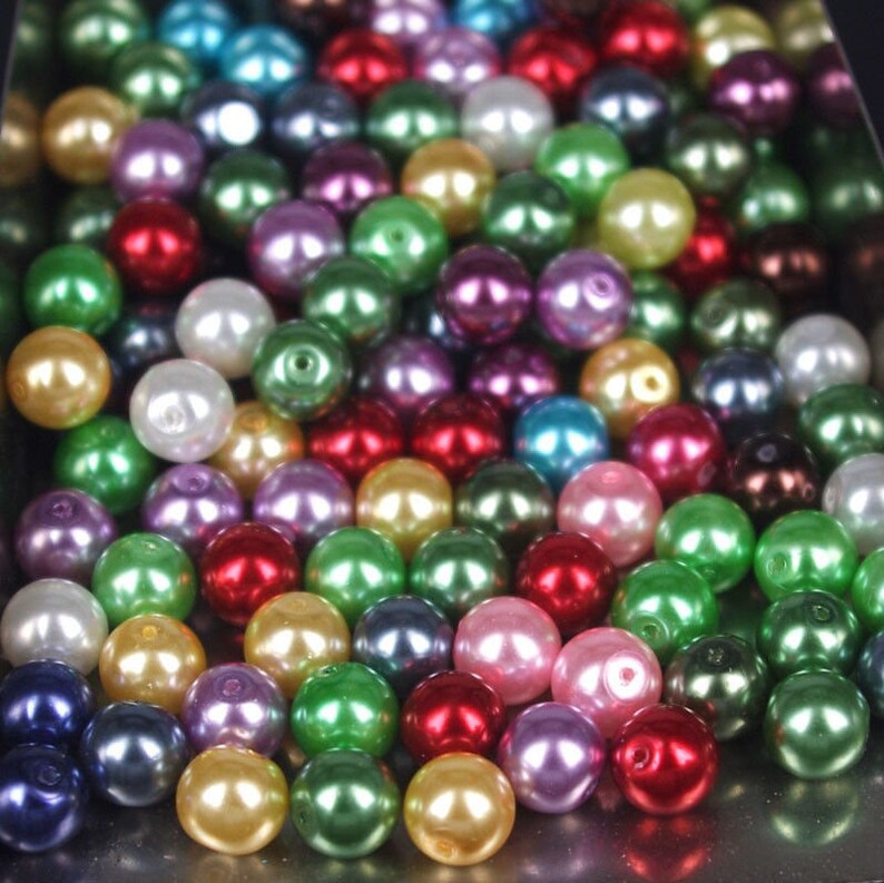 May include: A large assortment of colorful pearl beads. The beads are round and smooth, and they come in a variety of colors, including white, black, red, green, blue, and purple.