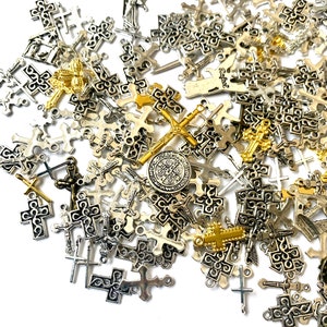 Peut inclure: Un grand assortiment de breloques en forme de croix argentées et dorées. Les breloques sont de différentes tailles et de différents designs, notamment des croix simples, des croix ornées et des croix avec des figures religieuses.