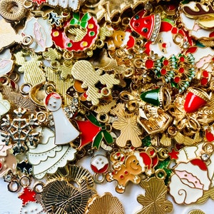 May include: A large assortment of gold-colored metal charms with various Christmas-themed designs. The charms feature a variety of colors, including red, green, white, and blue. Some of the charms are shaped like snowflakes, Christmas trees, bells, and Santa Claus.