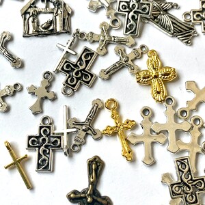 May include: A collection of silver and gold-toned metal charms featuring various Christian symbols, including crosses, crucifixes, and a nativity scene. The charms are perfect for jewelry making, scrapbooking, or other craft projects.