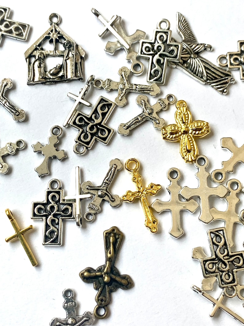 May include: A collection of silver and gold-toned metal charms featuring various Christian symbols, including crosses, crucifixes, and a nativity scene. The charms are perfect for jewelry making, scrapbooking, or other craft projects.