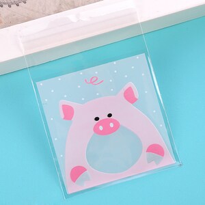 May include: Clear plastic bag with a pink pig design. The pig has a blue belly and pink ears, nose, and hooves. The bag has a white polka dot pattern and the word "e" in a swirl.