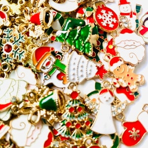 May include: Assortment of gold-tone Christmas charms with enamel details. The charms feature various holiday themes, including snowmen, Christmas trees, ornaments, and Santa Claus.