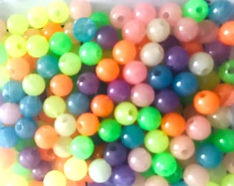 May include: A collection of round, smooth beads in a variety of vibrant colors including neon green, bright orange, soft pink, deep purple, and translucent blue. Each bead features a small, centered hole for threading, creating a dense, colorful pile.