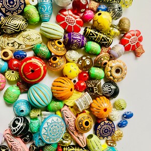 May include: A large collection of colorful wooden beads with various patterns and designs. The beads are made of wood and have a variety of shapes, including round, oval, and square. The beads are perfect for making jewelry, crafts, and other projects.