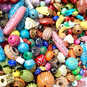 May include: A large assortment of colorful, patterned beads. The beads are made of various materials, including wood, plastic, and glass. They are all different shapes and sizes, and some have metallic accents. The beads are perfect for making jewelry, crafts, and other projects.