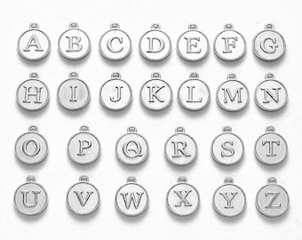 May include: A set of 26 silver metal alphabet letter charms. Each charm is a circle with a raised letter in the centre. The letters are A through Z.