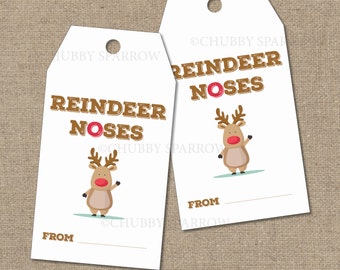 Può includere: Due etichette regalo bianche con un'illustrazione di renna e il testo "Reindeer Noses". La renna è marrone con il naso rosso e sta salutando. Le etichette hanno uno spazio per scrivere "Da".