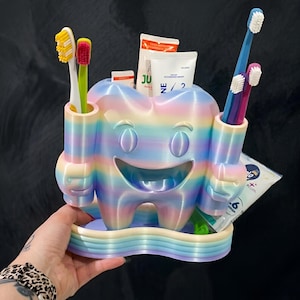 Puede incluir: Una taza de cerámica blanca con un asa negra y el texto "But First, Coffee" en negrita negra. La taza se encuentra sobre un fondo borroso, sugiriendo un ambiente acogedor.