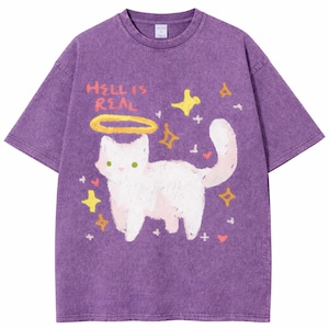 May include: Purple t-shirt with a graphic of a white cat wearing a halo, surrounded by stars and hearts. The text "HELL IS REAL" is above the cat. The shirt has a vintage, washed look.