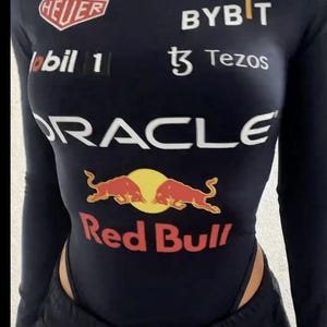 May include: Navy blue bodysuit with long sleeves and a mock turtleneck. The bodysuit features multiple logos, including "Red Bull", "Oracle", "Tag Heuer", and "Bybit". The Red Bull logo is prominently displayed on the chest.