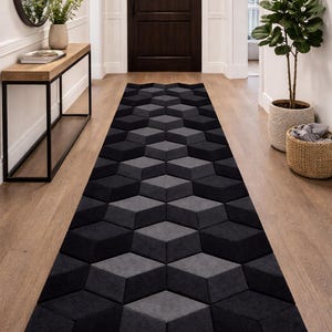 Può includere: Un lungo tappeto geometrico con un motivo a cubo 3D in tonalità di grigio e nero. Il tappeto è posato su un pavimento in legno in un corridoio, aggiungendo un tocco moderno al design degli interni. Le dimensioni del tappeto non sono visibili.