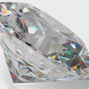 May include: A clear, colorless, faceted gemstone with a brilliant cut. The stone features numerous triangular and kite-shaped facets that reflect light, creating internal prismatic rainbow refractions and sharp geometric edges throughout.
