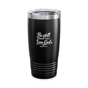 May include: Black insulated tumbler with a clear lid. The tumbler features the text "Be still & know that I am God" in white script, with "Psalm 46-10" below. The tumbler has a silver rim and a ridged base.