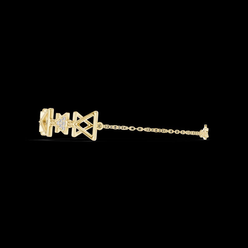 May include: A delicate gold-colored earring with geometric shapes and small, sparkling accents. The earring features a series of connected shapes, including triangles and squares, and a chain. The earring is set against a black background.