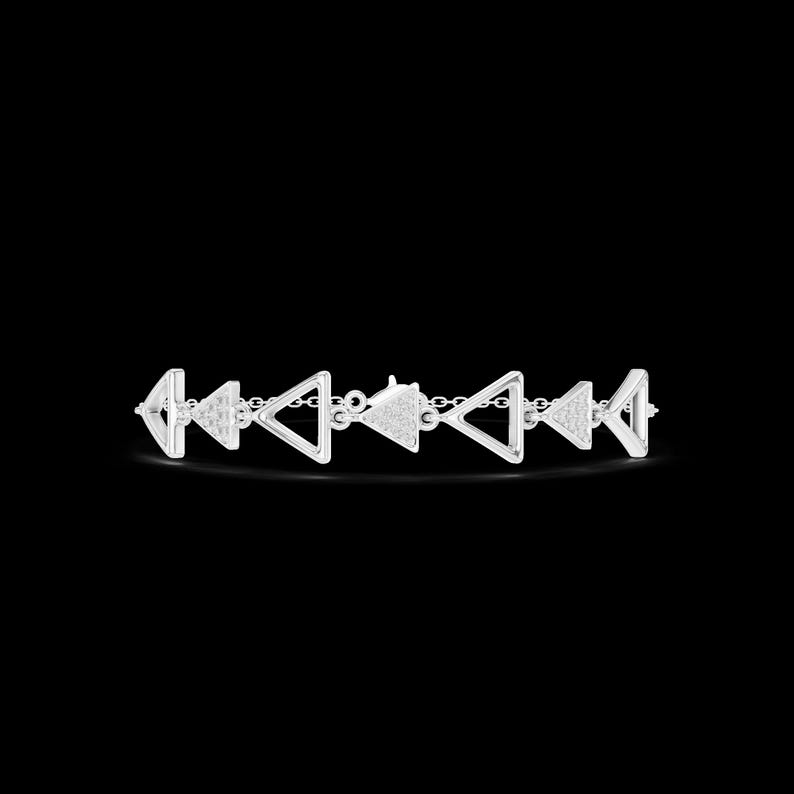May include: A silver bracelet featuring a series of open triangle shapes connected by small chain links. The triangles alternate between smooth and textured surfaces, creating a geometric pattern. The bracelet is set against a black background.