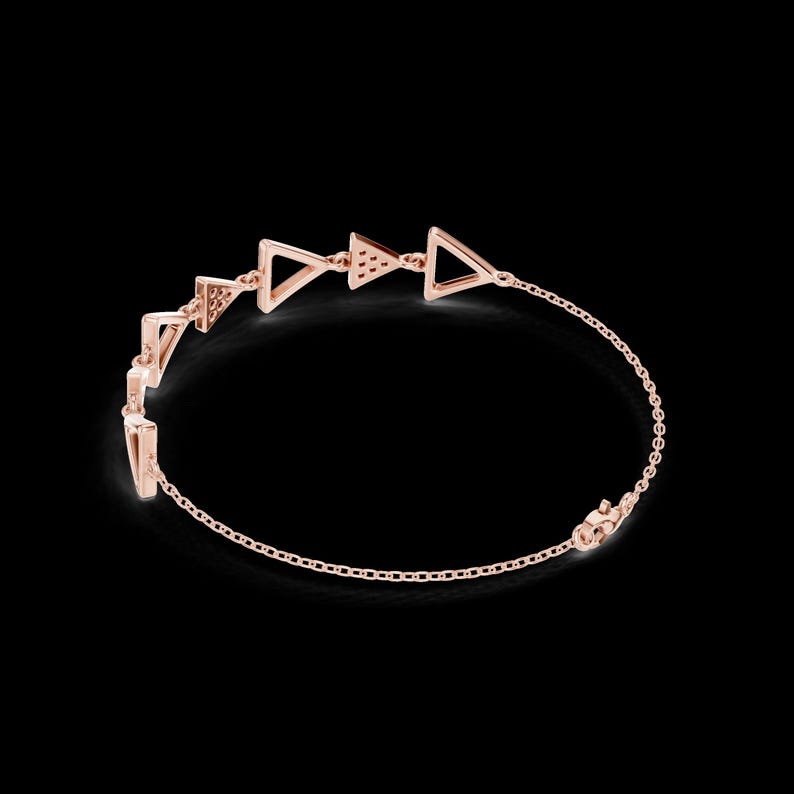 May include: Rose gold bracelet featuring a series of openwork triangles connected by delicate chain links. The triangles are evenly spaced and have a geometric design. The bracelet is set against a black background.