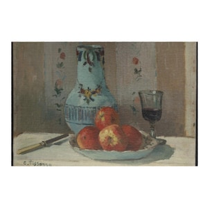 以下が含まれることがあります： 花柄のアクセントが付いた水色の花瓶、赤いリンゴの皿、赤い液体が入ったグラス、ナイフを描いた静物画。背景には花柄があります。絵画は左下に署名されています。