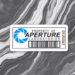 Puede incluir: Una pegatina rectangular blanca con el texto "PROPERTY OF APERTURE LABORATORIES" en negro y un logotipo azul y blanco. La pegatina también presenta un código de barras y el texto "ZM00250". El fondo es un patrón gris y blanco veteado.