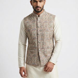 Può includere: Un gilet beige a fantasia multicolore con collo alla coreana e chiusura con bottoni. Il gilet è indossato sopra una camicia color crema a maniche lunghe e pantaloni abbinati. L'outfit è uno stile tradizionale.